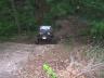 1977 Chevrolet Blazer - An off-road vehicle navigates a dirt path surrounded by trees and foliage.