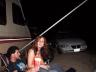 1977 Chevrolet Blazer - People relax at a campsite next to an RV, with a car visible in the background after dark.