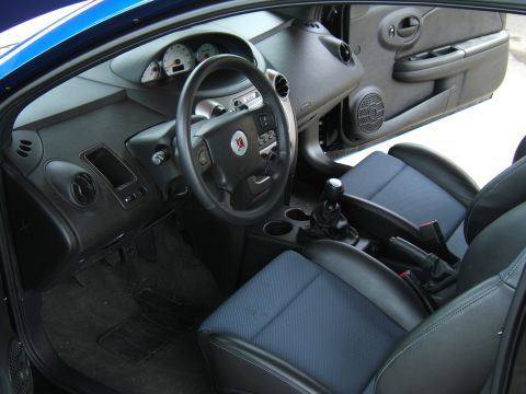 1998 Ford Taurus - The interior of a blue car is shown, blue fabric seats with black leather bolsters and a manual transmission shifter.