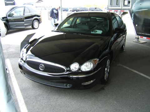 1998 Ford Taurus - Black Buick sedan parked outdoors, showing its front grille and headlights. Another car is visible to the left.