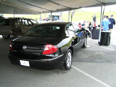 1998 Ford Taurus - A black sedan is parked under a tent, with a minivan visible to its left.