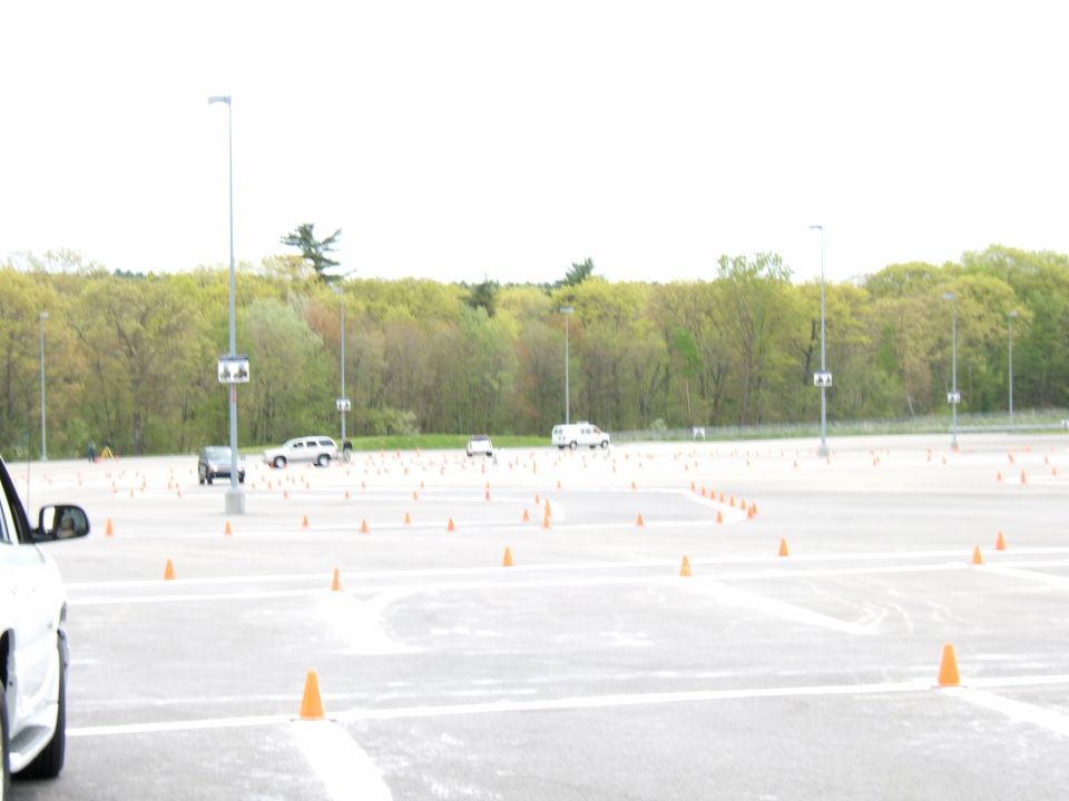 Parking lot with traffic cones and several cars visible in the distance under an overcast sky
