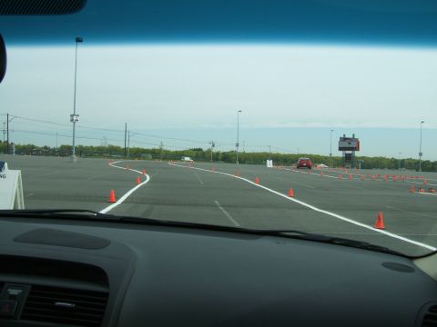 1998 Ford Taurus - A red car navigates a cone course in a large parking lot under an overcast sky.