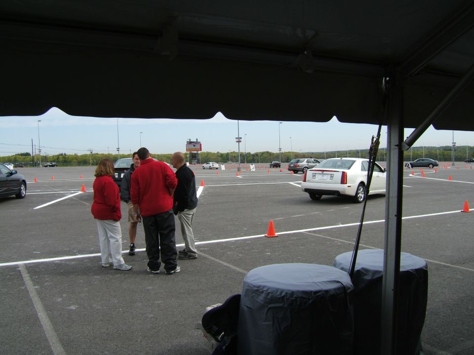 White sedan seen from the rear on a track with orange cones