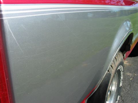 1995 Ford Bronco - Scratched two-tone paint on a vehicle's side panel, showing the fender and tire.