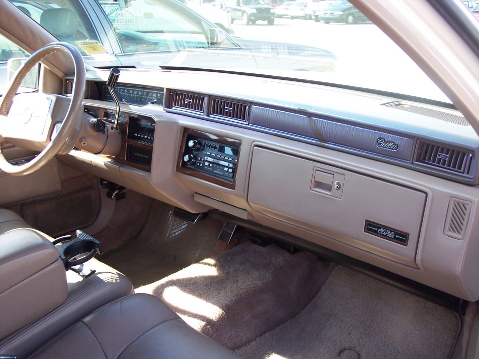 Tan Cadillac DeVille dashboard interior with wood trim, radio, and glovebox