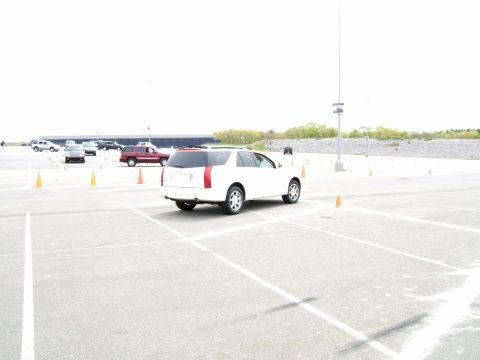 1998 Ford Taurus - A white SUV navigates a course marked by orange cones in a large, empty parking lot.