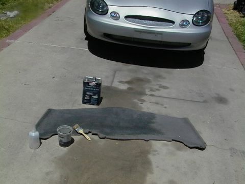 1999 Ford Taurus - A 1999 Ford Taurus is parked on a driveway next to cleaning supplies and a car mat.