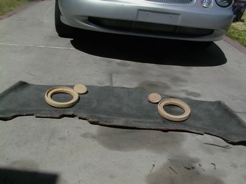 1999 Ford Taurus - Speaker mounts are laid out on a carpeted panel in front of a silver car.
