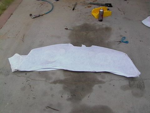 1999 Ford Taurus - A car hood is covered with white paper on a concrete surface, surrounded by tools like scissors and a spray can.
