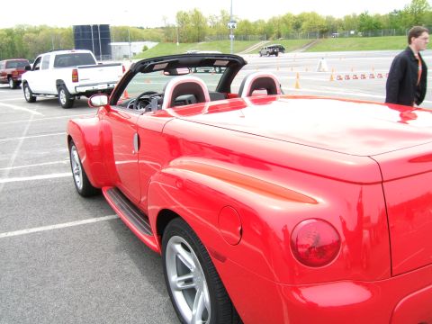 1998 Ford Taurus - A red convertible sports car is parked in a lot, with other vehicles visible in the background.