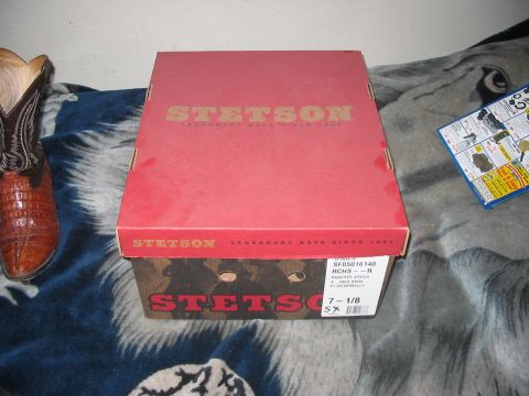 1986 Ford Bronco - A Stetson hat box and a cowboy boot are displayed on a blanket, with a small informational pamphlet nearby.