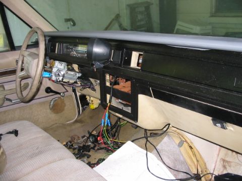 1985 Ford LTD Crown Victoria - The dashboard of a car is disassembled, revealing a complex network of wires and electrical components.