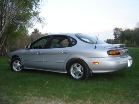 1999 Ford Taurus - Silver 1999 Ford Taurus sedan parked on grass with trees in the background.