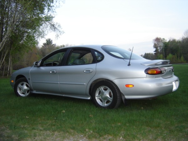 Silver 1999 Ford Taurus sedan parked on grass, rear quarter view