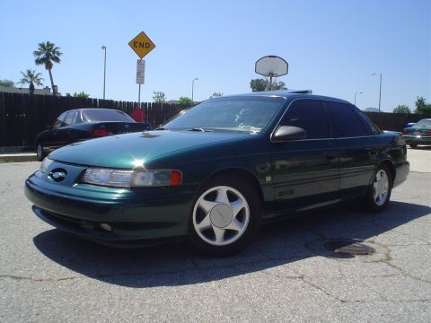 1993 Ford Taurus - A green sedan is parked on a sunny day, with a basketball hoop and an 'END' sign in the background.