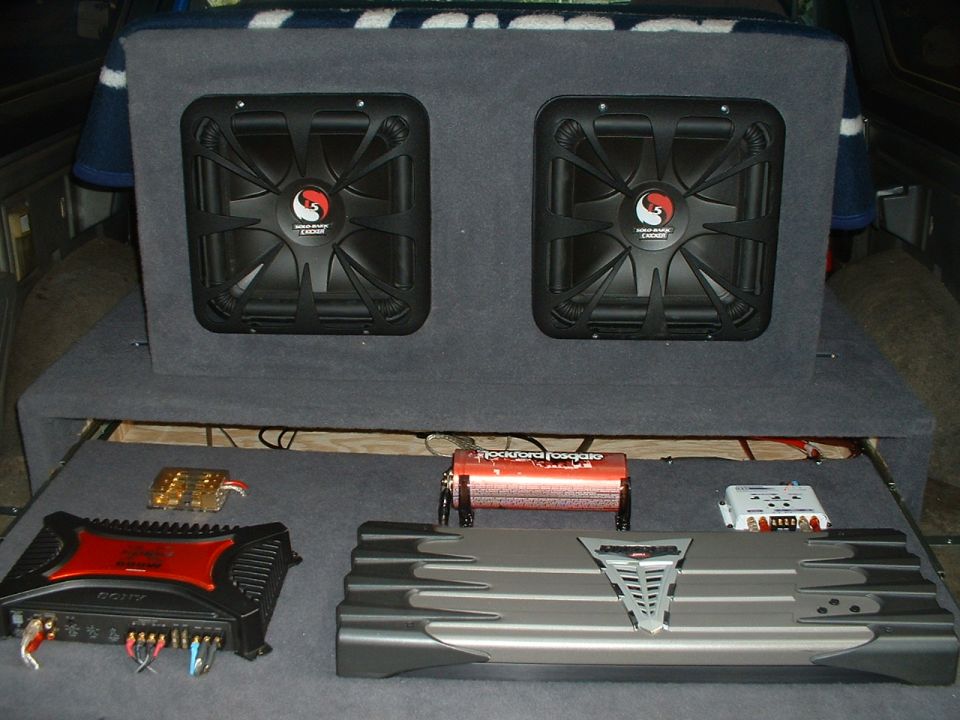 Car interior with two subwoofers in a box and audio amplifiers on a shelf