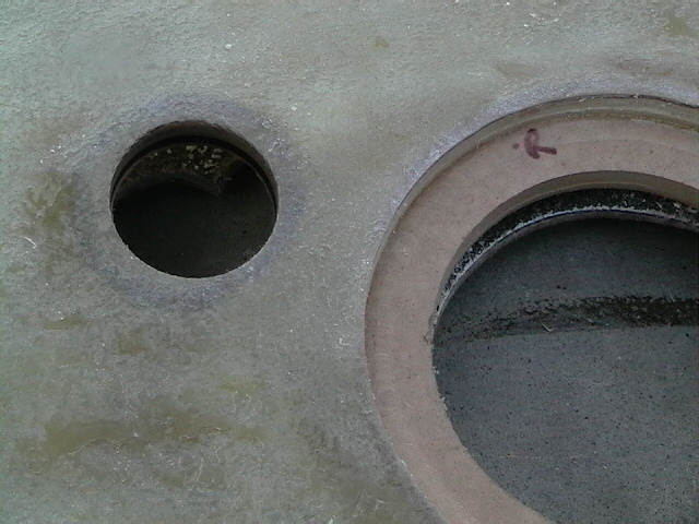 Close-up of two circular openings in a textured surface with a red arrow mark