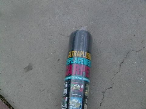 1999 Ford Taurus - A roll of replacement carpet is shown on a concrete surface, with product details visible on the packaging.