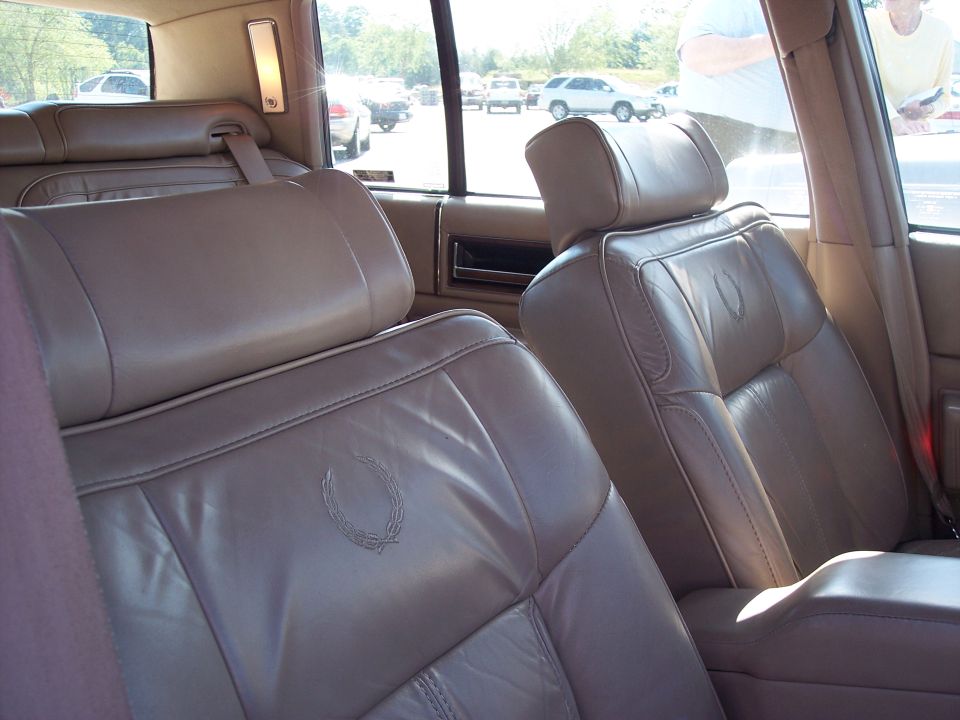 Tan leather Cadillac front seats with wreath crest emblems, viewed from rear