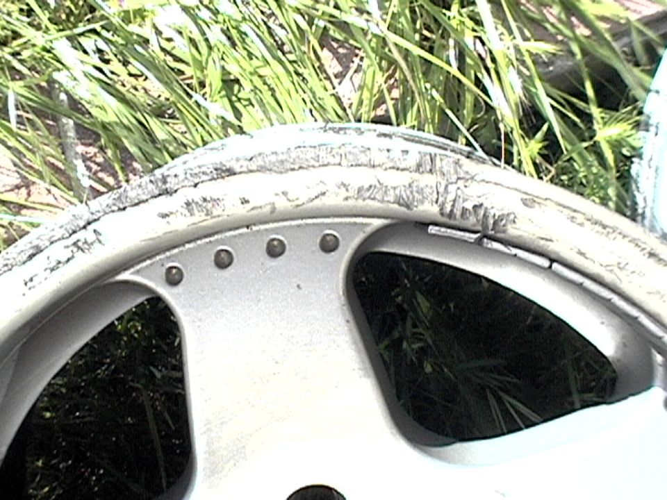 Damaged silver alloy wheel rim with visible curb rash and dents on the outer edge