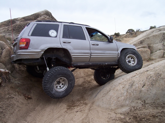 Silver 1999 Jeep Grand Cherokee climbing rocks with lifted suspension