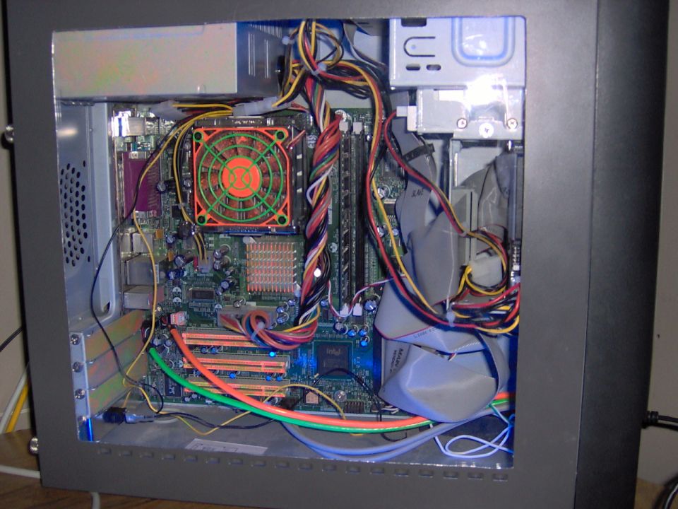 Inside of a computer case showing motherboard, orange CPU fan, and colorful cables