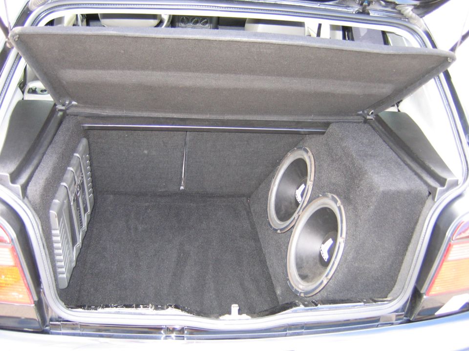 Car trunk interior with a custom subwoofer box holding two large speakers and a smaller speaker box on the left