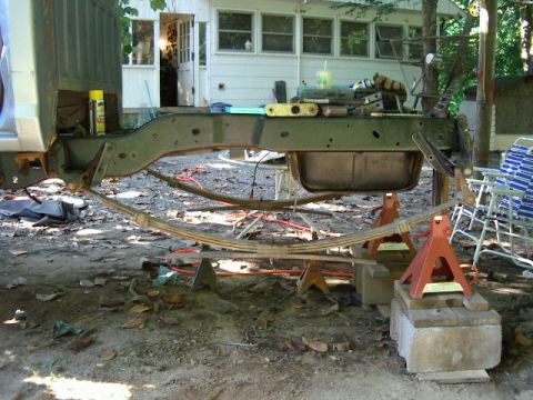 1985 Ford Bronco - Truck frame and suspension components are supported by jack stands in a yard.