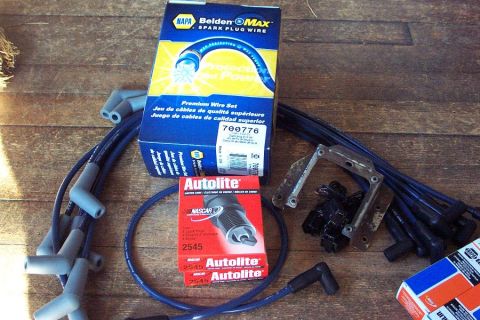 1985 Ford Crown Victoria LTD - A collection of automotive ignition parts, including NAPA Belden Max spark plug wires and Autolite spark plugs, are laid out on a wooden ta…