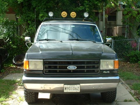 1989 Ford Bronco - This 1989 Ford Bronco features a front-end view with distinctive smiley face lights mounted on its roof rack.