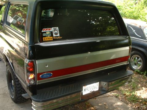 1989 Ford Bronco - The rear of a Ford Bronco shows its taillights, bumper, and a Ford emblem. A license plate and several stickers are visible on the rear.