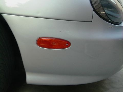 1999 Ford Taurus - The front fender of a silver car features an amber marker light and part of the headlight assembly.