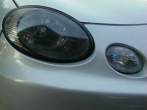 1999 Ford Taurus - Close-up of a silver car's front end, showing the headlight and fog light assembly.