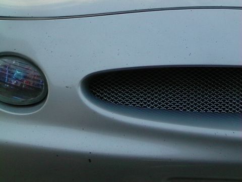 1999 Ford Taurus - Close-up of a silver car's front grille and headlight, with a SuperMotors.net watermark visible.