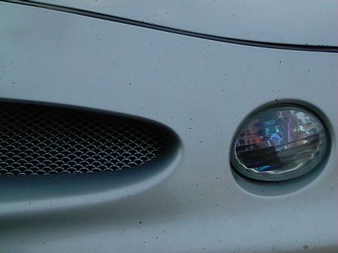 1999 Ford Taurus - A close-up view of a vehicle's front grille and headlight assembly, with visible dust and debris on the surface.