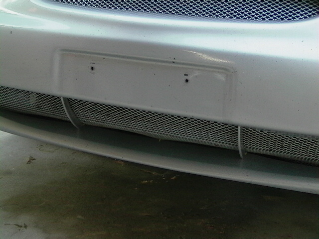 White car front bumper with mesh grille and license plate mount