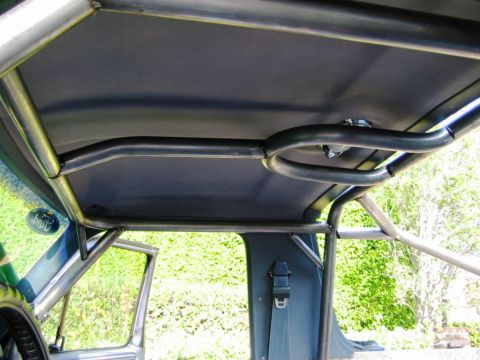 1985 Ford Bronco - The interior of a vehicle is shown with a custom-installed roll cage, obscuring the original roof.