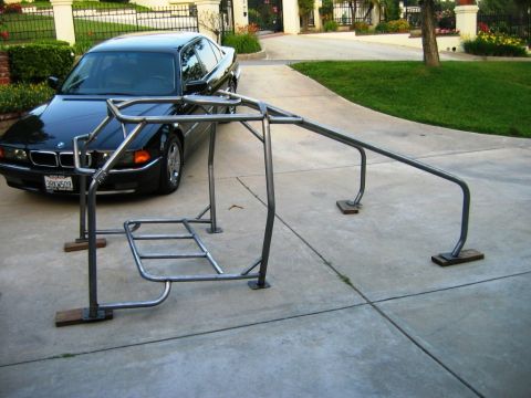 1985 Ford Bronco - Custom roll cage assembly on a driveway, with a black sedan parked behind it.