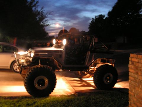 1978 Ford Bronco - An off-road vehicle with a roll cage and large tires is parked outside at dusk.