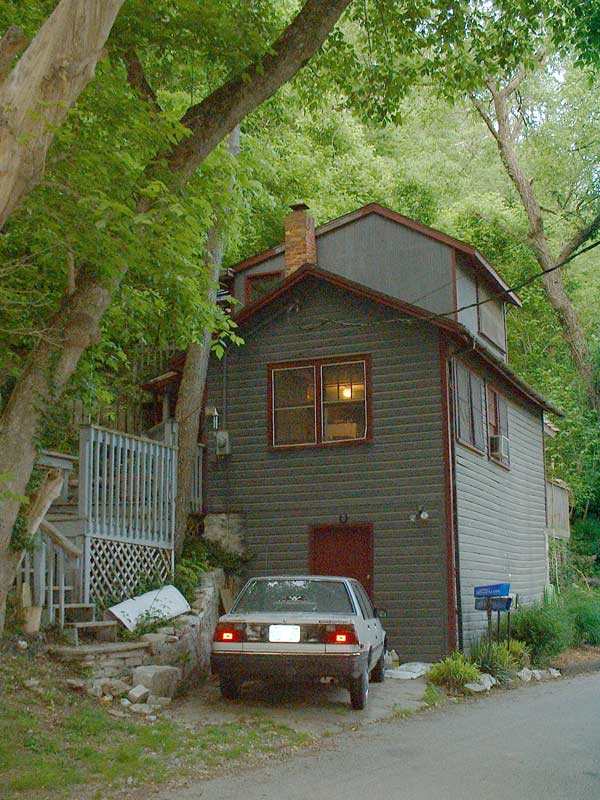 Rear view of a light-colored 1980s sedan parked in front of a house