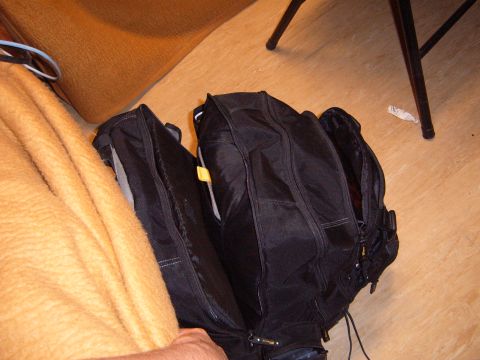 1988 Ford Bronco - A black backpack is open on the floor, with a blanket and chair legs visible in the background.