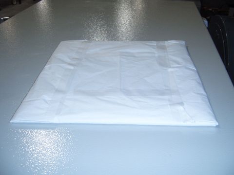 1988 Ford Bronco - Object wrapped in white paper and taped, placed on a textured grey surface.