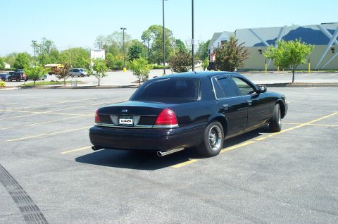 1999 Ford Crown Victoria - A black sedan is parked in a lot, showing its rear and side profile.