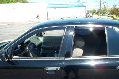 1999 Ford Crown Victoria - Side view of a black sedan, revealing its interior and exterior details, including installed weather visors.