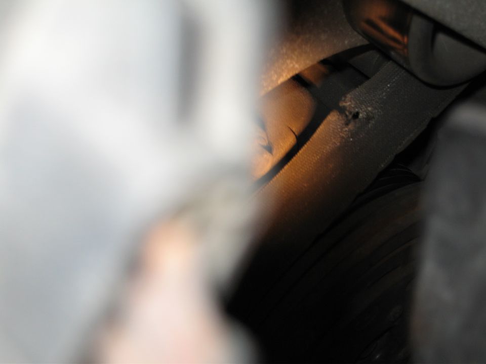 Close-up of a damaged engine hose with a visible hole and frayed edges