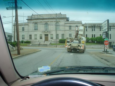 1981 Ford Bronco - A utility truck drives away from the camera on a street with a large building in the background.
