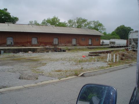 1981 Ford Bronco - Railroad cars are visible next to a brick industrial building under a cloudy sky.