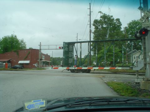 1981 Ford Bronco - A train is stopped at a railroad crossing, blocking traffic. A person stands on one of the train cars.