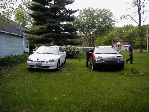 1997 Ford Taurus - Two 1997 Ford Taurus sedans are parked in a grassy area next to a house.